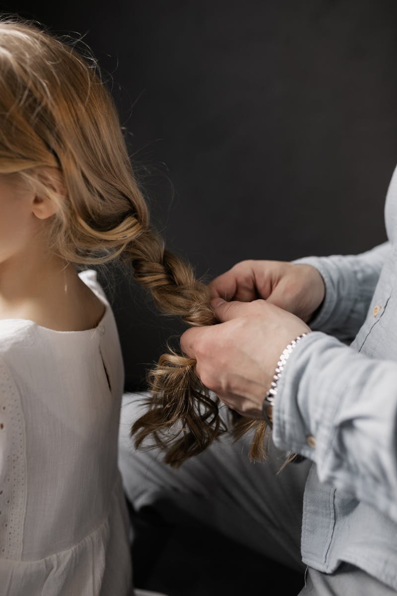 Close-up of a grandparent braiding a young girl's hair, highlighting family bonding