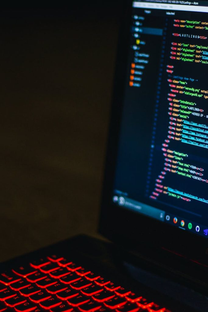 Red backlit keyboard and code on laptop screen create a tech-focused ambiance.